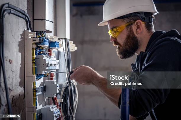 A Male Electrician Works In A Switchboard With An Electrical Connecting Cable Stock Photo - Download Image Now