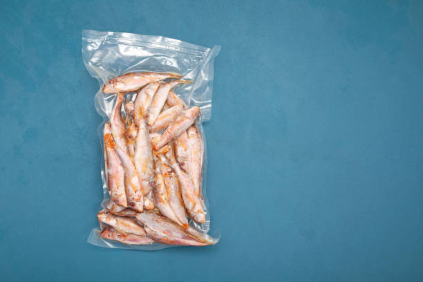 istock Frozen fish Mullus barbatus (red mullet) in transparent pack on blue background. Goatfish found in Mediterranean Sea, Black Sea and eastern North Atlantic Ocean. Top view, copy space 1353481063