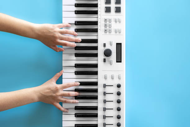 istock Female hands play musical keys on a blue background, top view. 1353482266
