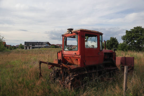 Old red abandoned tractor with broken windows in the field
