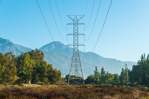 High voltage power line tower carries vital electricity from power generation hub into remote rural mountain communities.