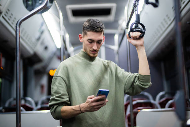 Young handsome man using phone in public transportation stock photo