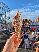 istock Ice Cream Cone held up at Coney Island, New York 1353495271