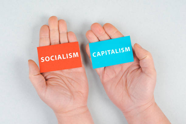 słowa socjalizm i kapitalizm stoją na kartce papieru, ręce trzymają przesłanie, kwestia polityczna - socialism zdjęcia i obrazy z banku zdjęć