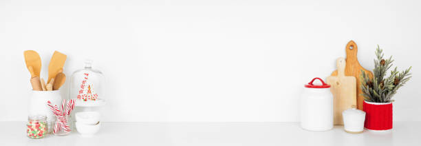 Christmas kitchenware, decor and sweets on a white shelf against a white wall banner background