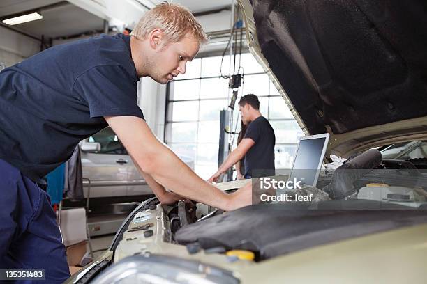 Mecánico Usando Computadora Portátil Mientras Trabaja En Automóvil Foto de stock y más banco de imágenes de Mecánico de coches