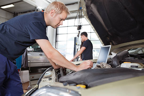 istock Mechanic using laptop while working on a car under the hood 135351483