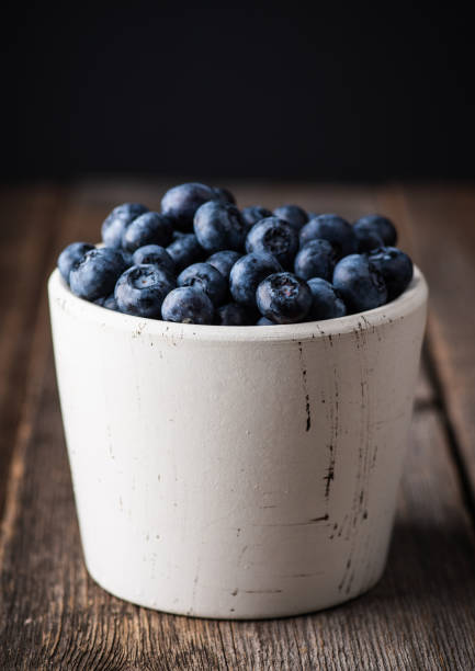 istock Blueberries in white ceramic bowl on rustic wooden background. Selective focus. Shallow depth of field. 1353527582