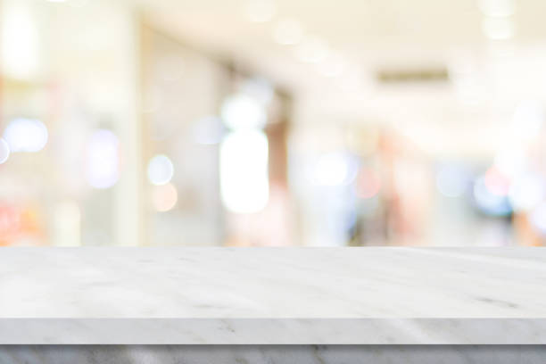 istock Empty white table top, counter, desk over blur perspective store with bokeh light background, White marble stone table, shelf and blurred shop for food, product display mockup, template backdrop, banner, Retail business wallpaper, poster 1353528439