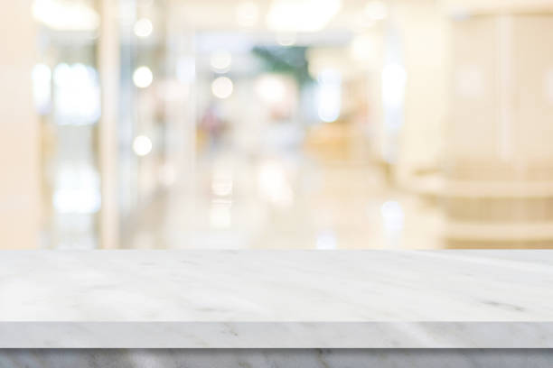 istock Empty white table top, counter, desk over blur perspective store with bokeh light background, White marble stone table, shelf and blurred shop for food, product display mockup, template backdrop, banner, Retail business wallpaper, poster 1353528460