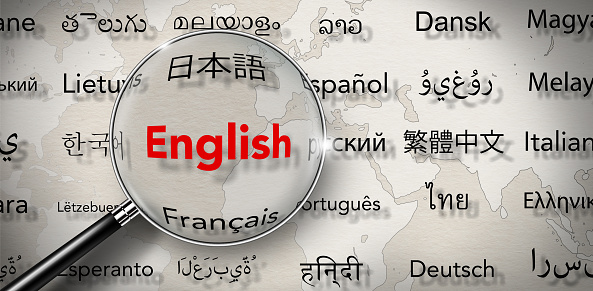 Magnifying glass with Word of English and Several important languages on paper with world map background.  Words cloud, Translate, and languages education concept.