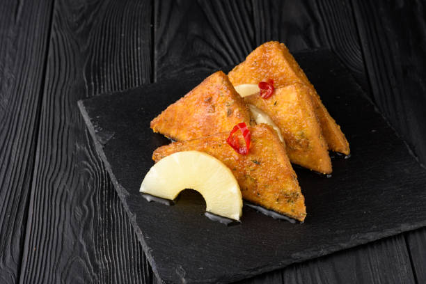 istock Fried tofu with pineapple on a black wooden background. 1353544709