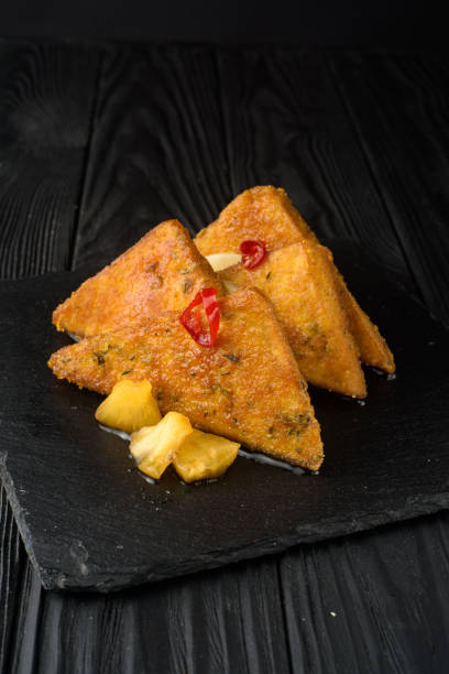 istock Fried tofu with pineapple on a black wooden background. 1353544724