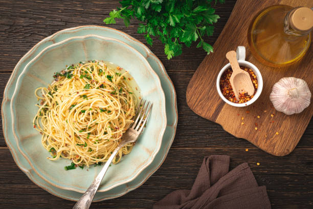 piatto top view di spaghetti aglio e olio e ingredienti su fondo di legno - garlic cooking oil cutting board horizontal foto e immagini stock
