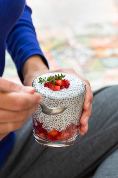 Female hands holding chia pudding with fresh strawberries for breakfast Vegan healthy eating and dieting food concept. Female hands holding chia pudding with fresh strawberries for breakfast eating chia seeds stock pictures, royalty-free photos & images