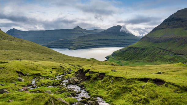 Faroe Islands Funningsfjordur Fjord Mountain View to Kalsoy Eysturoy Island Faroe Islands panorama of Funningsfjordur Fjord and surrounding Funningsfjørður Mountain Range in summer under summer cloudscape. North Coast of Eysturoy Island - Faroe Islands Panorama, Kalsoy Island in the background. Funningsfjørður - Funningsfjordur Fjord, North-East Coast of Eysturoy Island, Faroe Islands, Kingdom of Denmark, Nordic Countries, Europe. eysturoy photos stock pictures, royalty-free photos & images