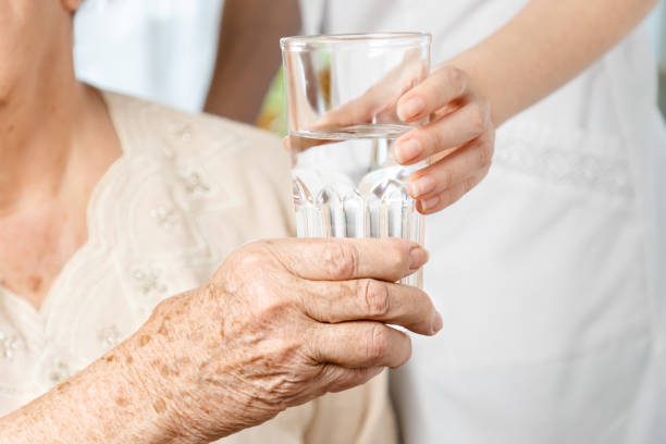 dia internacional das pessoas idosas. uma enfermeira dá um copo d'água para uma idosa. feche as mãos. cuidados com idosos em asilos - water divide - fotografias e filmes do acervo