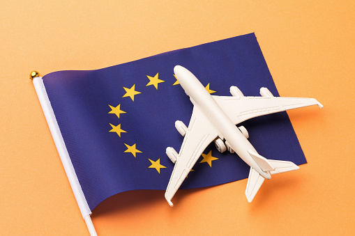 EU flag and toy plane on orange background, concept of flights to the European Union