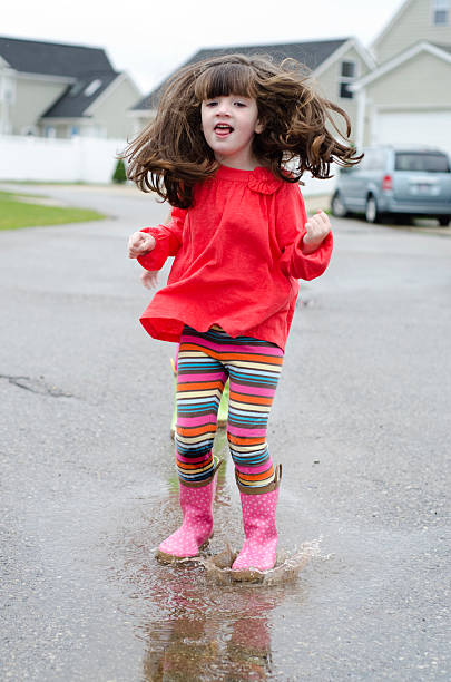 istock girl jumps in rain puddes 135354865