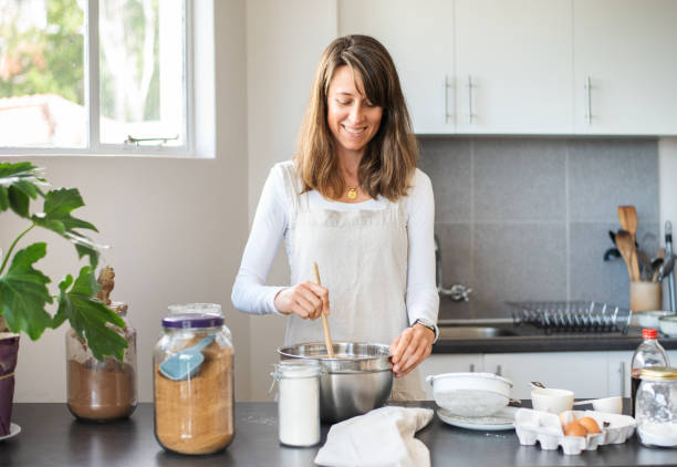 istock Smiling young woman making a dessert at home in her kitchen 1353551348