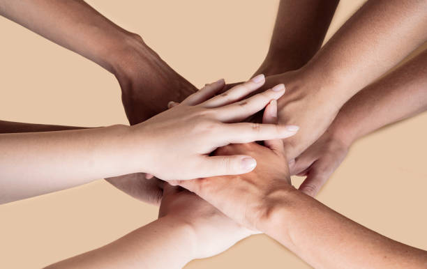istock joined hands of multiethnic women, beige background 1353551684