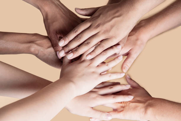 istock joined hands of multiethnic women, beige background 1353551689
