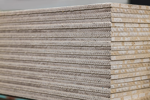 A stack of gypsum fiber sheet moisture-resistant close-up, texture.