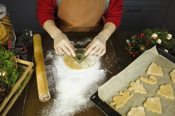 женщина в оранжевом фартуке готовит печенье. - baking paper cookie tray стоковые фото и изображения