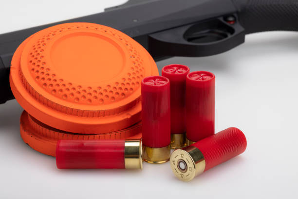 istock Clay disc flying target and shotgun with bullet shell on white background ,Clay shooting game 1353554414