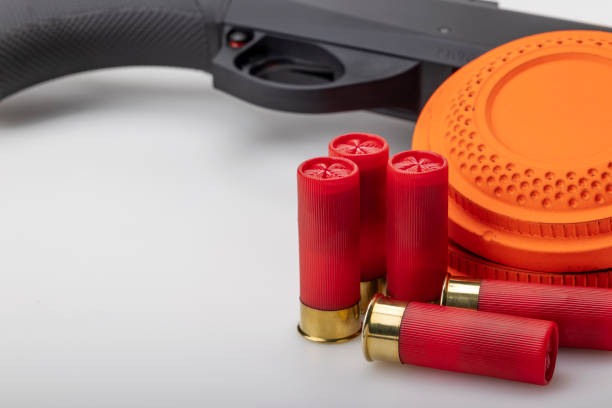 istock Clay disc flying target and shotgun with bullet shell on white background ,Clay shooting game 1353554416
