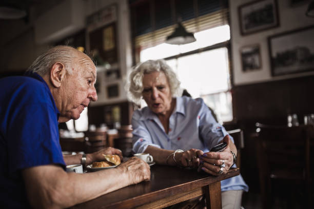istock Senior couple using smart phone in cafe 1353555135