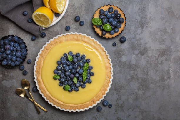 Blueberry and lemon curd tart on dark grey stone table. Top view. Copy space.