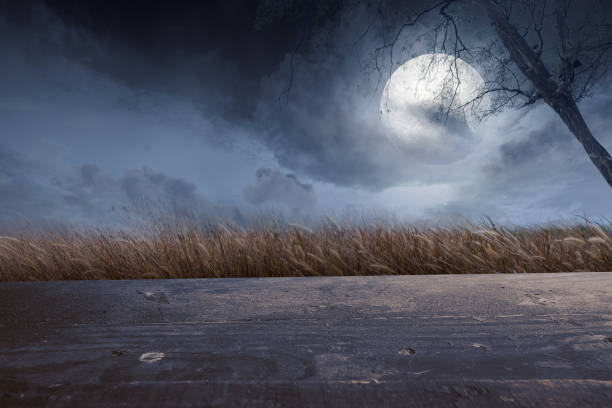 istock Wooden table with a full moon with dark cloudscapes on the night 1353558636