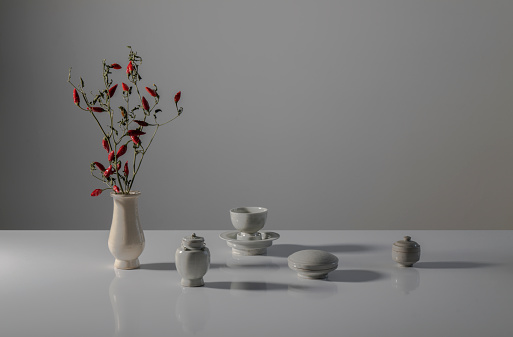 Still life of Chinese antique white porcelains and branch of red chili pepper on white table