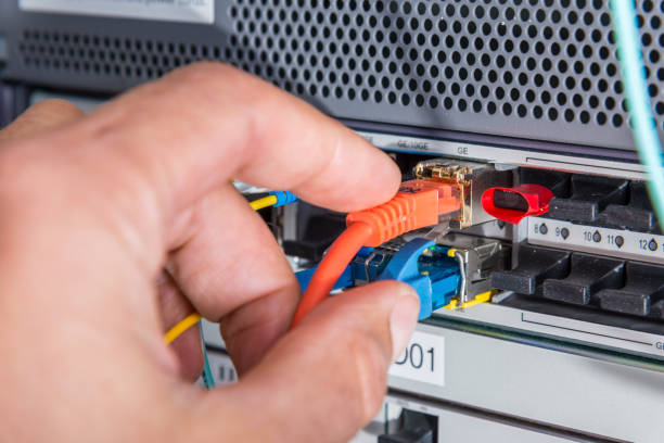 istock Hand of computer engineer connecting fiber optic cable 1353559814