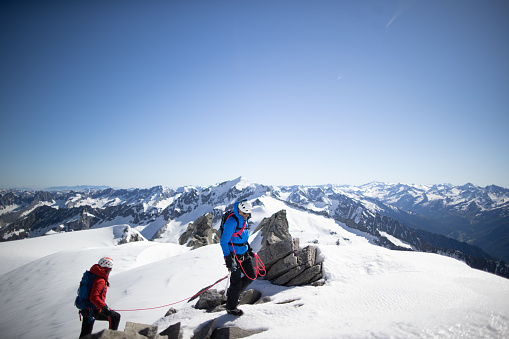 Two people hiking in snow covered mountains.