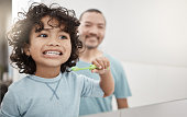 istock Shot of an adorable little boy brushing his teeth in a bathroom with his father at home 1353561573