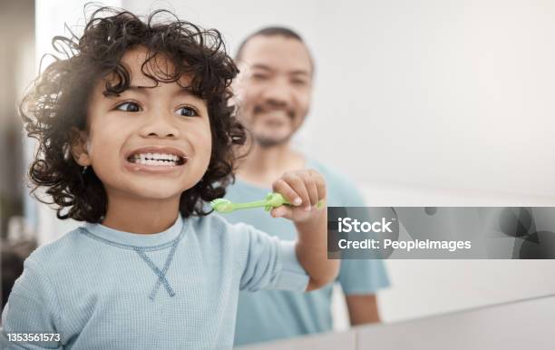 Shot Of An Adorable Little Boy Brushing His Teeth In A Bathroom With His Father At Home Stock Photo - Download Image Now