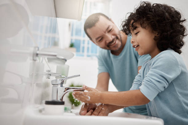 tiro de um pai ajudando seu filho a lavar as mãos e o rosto em uma torneira em um banheiro em casa - sink - fotografias e filmes do acervo