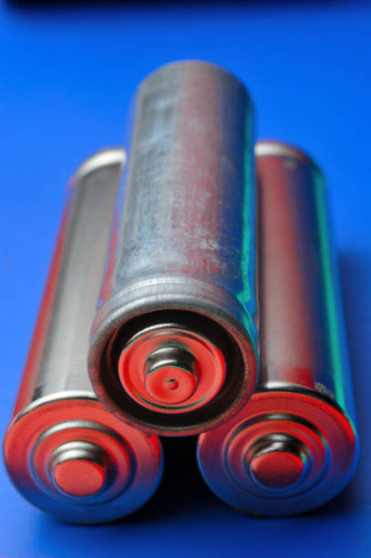 istock three beautifully illuminated finger-type batteries on a blue background. close-up 1353564135