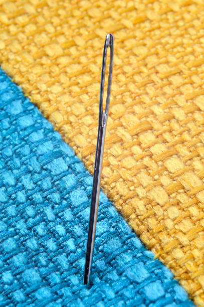 istock sewing needle on a yellow fabric background. close-up. 1353567742