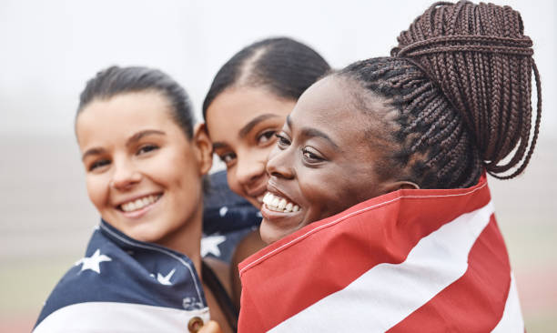 istock Shot of female athletes celebrating their win while holding a flag 1353570708