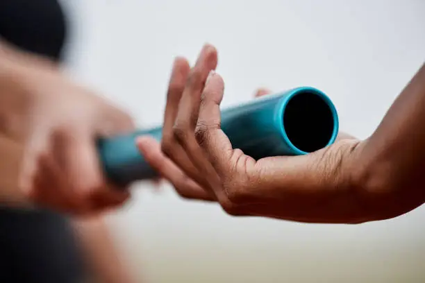 Photo of Shot of two athletes passing a baton during a relay race