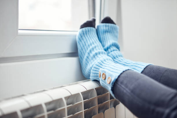 istock Woman's feet with woolen socks, enjoying inside home on the radiator. 1353571119