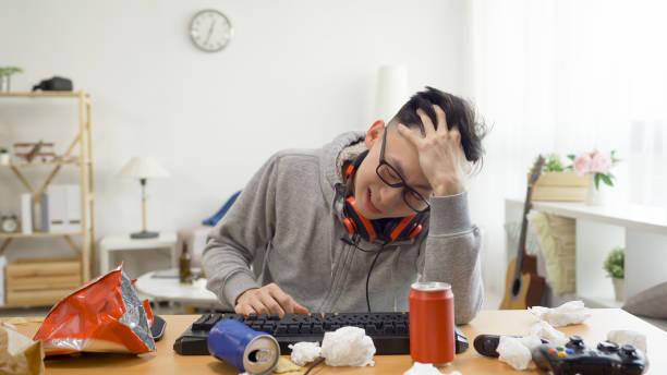 emocional jovem asiático nerd homem gamer joga jogos de computador e se sentindo nervoso. cara geek perder competição on-line com rosto chateado classificando cabelo testa. triste homem interior ficar em casa nas férias de verão - male education college student nerd - fotografias e filmes do acervo