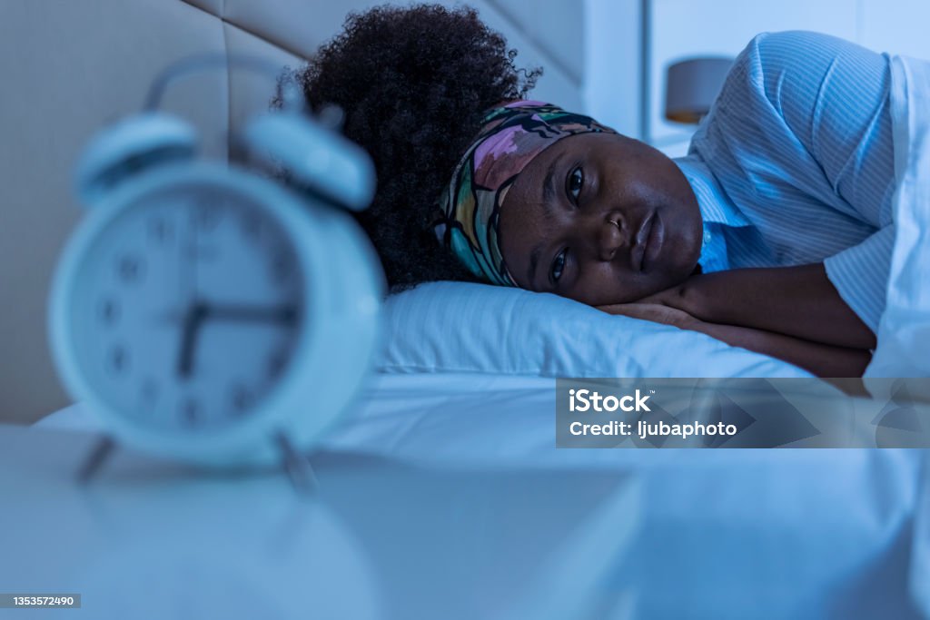 Depressed young woman lying in bed and feeeling upset after quarrel with her boylfriend in bed at home Sleeping Stock Photo