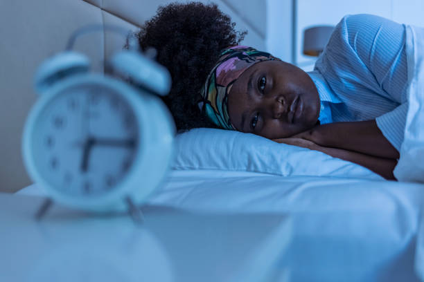 depressed young woman lying in bed and feeeling upset after quarrel with her boylfriend in bed at home - female emotional stress african ethnicity loss imagens e fotografias de stock