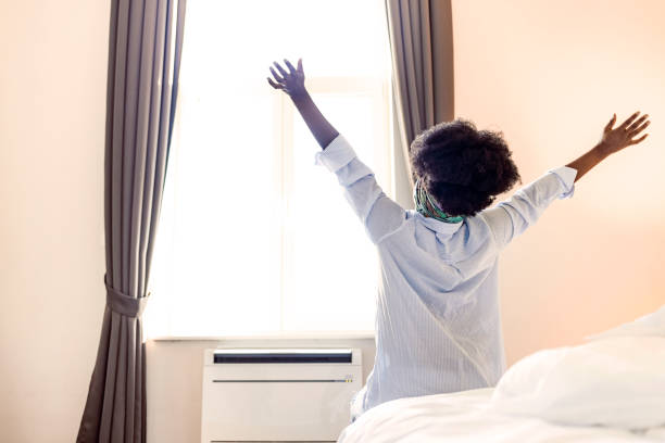 istock Happy woman stretching in bed after waking up 1353572651