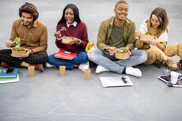 istock Students eating salad during lunch on asphalt 1353572799