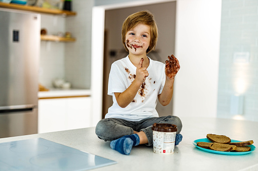 Cute little boy with chocolate stains on a kitchen counter.